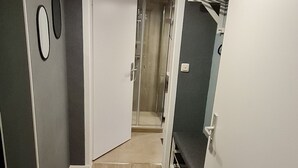 A narrow hallway with wooden flooring, a white door, and a glass shower area. - Charming old town apartment within 3 minutes walking distance to the city center (Worms)