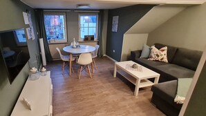 A compact living space with a dining area, a sofa, and a TV mounted on the wall. - Charming old town apartment within 3 minutes walking distance to the city center (Worms)