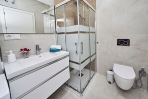 A modern bathroom with a glass-enclosed shower, a white sink with a mirror, and a toilet. - Csa Isolde: Cozy and Modern (Nerja)