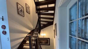 A spiral staircase with a chandelier, framed artwork, and a window with a view. - Cozy, quiet guest room with bathroom in a dream villa on the edge of the forest (Michendorf)