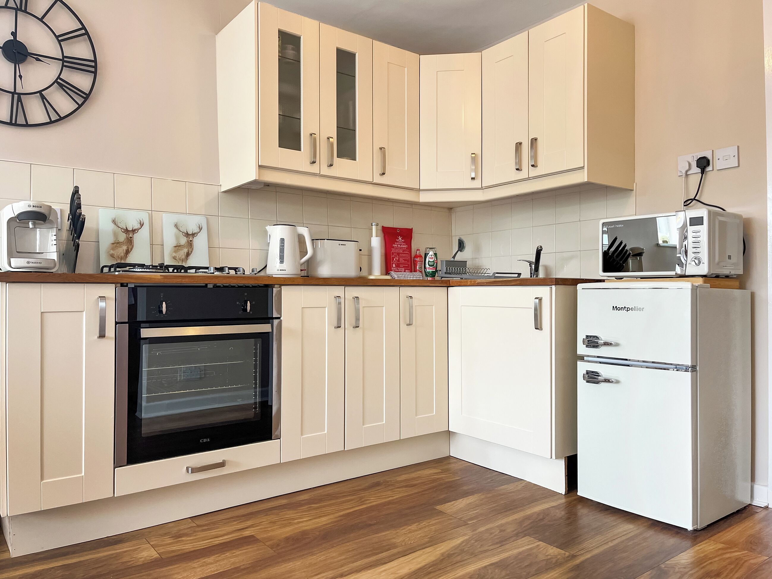 A kitchen with white cabinets, a Bosch coffee maker, a microwave, and a CBA oven.