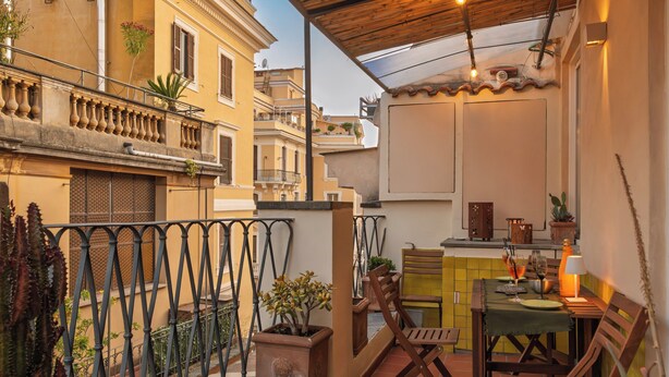 A small patio with a table, chairs, and a potted plant. - Delightful Penthouse in the heart of Monti within walking distance metro Cavour and Colosseum. (Roma)