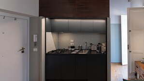 A compact kitchen with a black countertop, a tiled backsplash, and a built-in stove. - Delightful Penthouse in the heart of Monti within walking distance metro Cavour and Colosseum. (Roma)