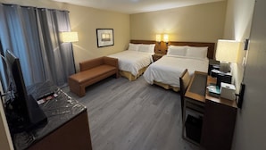 A hotel room with two beds, a desk, a TV, and a couch. - Kenricia Hotel (Kenora)