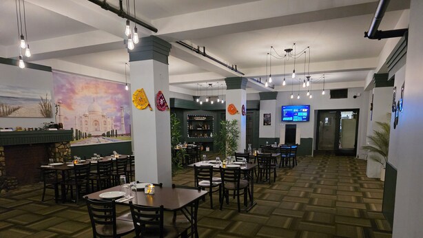 A restaurant with multiple tables and chairs, a bar area, and a mural on the wall. - Kenricia Hotel (Kenora)