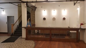 A reception desk with a wooden finish, a glass partition, and two wall-mounted clocks. - Kenricia Hotel (Kenora)