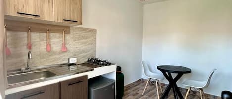 Une cuisine moderne avec des meubles en bois, une cuisinière à gaz et un évier. On y trouve également un coin repas avec une table ronde et deux chaises.