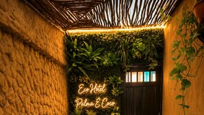 A hot tub with a neon sign, surrounded by greenery and wooden walls. - eco hotel palma É coco (San Andrés)