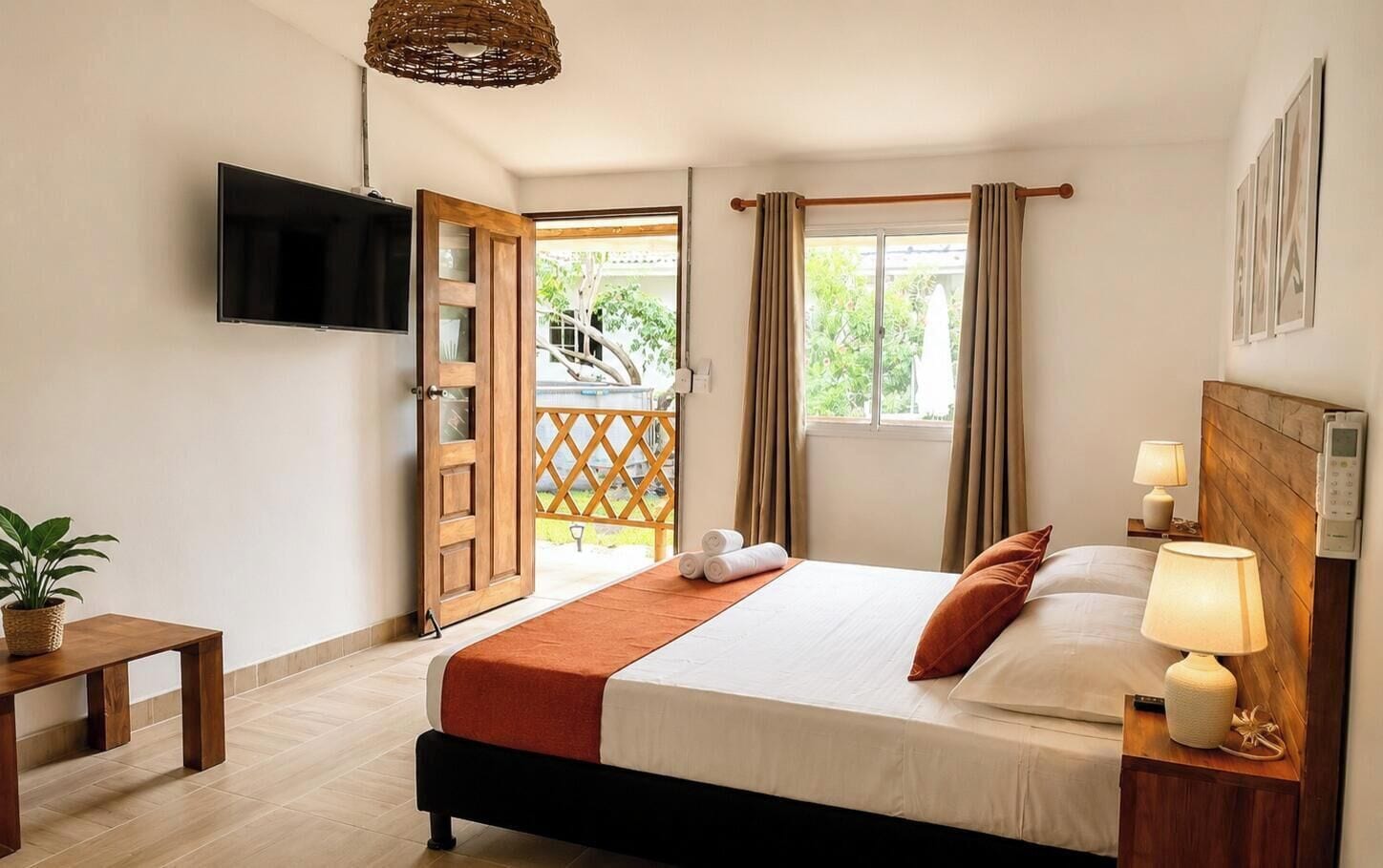Quarto de hotel com cama, mesa de cabeceira, abajur e televisão na parede.