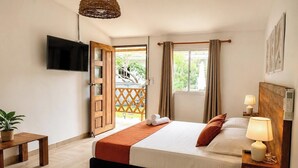 A hotel room with a bed, bedside table, lamp, and a TV mounted on the wall. - eco hotel palma É coco (San Andrés)