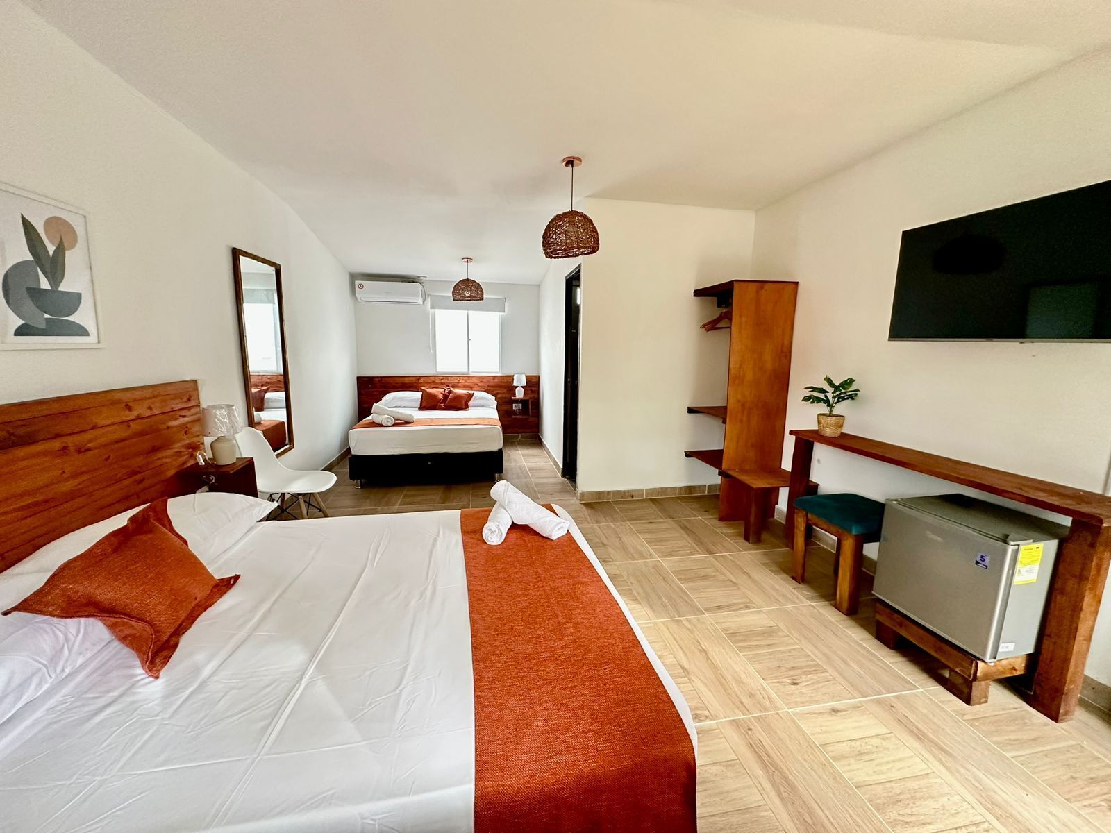 Une chambre d’hôtel avec un grand lit, un bureau, une chaise, une télévision et un petit réfrigérateur.