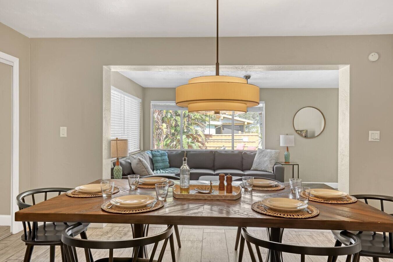 A dining area with a wooden table, six chairs, and a hanging light fixture.
