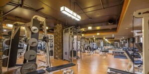 Ein Fitnessstudio mit Kurzhanteln, darunter eine Langhantelbank und verschiedene Kraftgeräte.