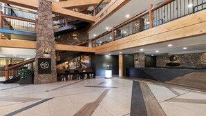 A multi-level lobby with a stone pillar, wooden railings, and a reception desk.