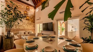 A dining area with a round glass table set for six, surrounded by chairs. - Casa Bovedas - 5 Bedroom Paradise (Cartagena de Indias)
