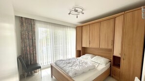 A bedroom with a bed, wooden wardrobe, a desk, and a chair. - Apartment in Middelkerke Near the Beach (Middelkerke)