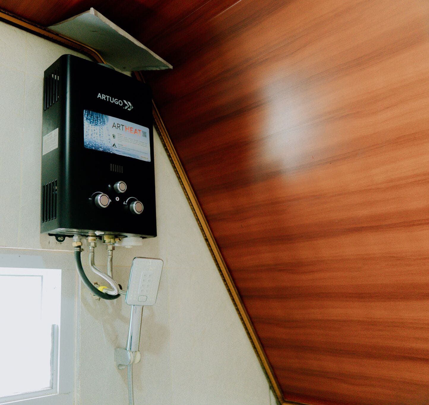 A wall-mounted air heater with control knobs and a digital display, connected to a wall-mounted thermostat.