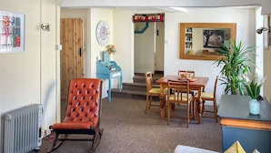 A cozy living room with a red leather chair, wooden dining table, and a sofa with colorful cushions. - 3 bedroom accommodation in Brecon (Brecon)