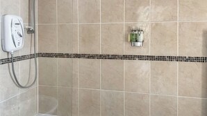 A bathroom with a bathtub, a handheld showerhead, and a wall-mounted faucet. - 3 bedroom accommodation in Brecon (Brecon)