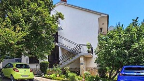 A two-story building with a staircase leading to a balcony, surrounded by greenery. - Lovely apartment in Jadranovo with WiFi (Jadranovo)