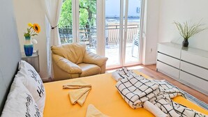 A bedroom with a bed, a chair, a dresser, and a view of the outdoors. - Lovely apartment in Jadranovo with WiFi (Jadranovo)