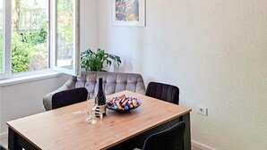 A dining area with a wooden table, four chairs, a bowl of snacks, a wine bottle, and a potted plant. - Lovely apartment in Jadranovo with WiFi (Jadranovo)