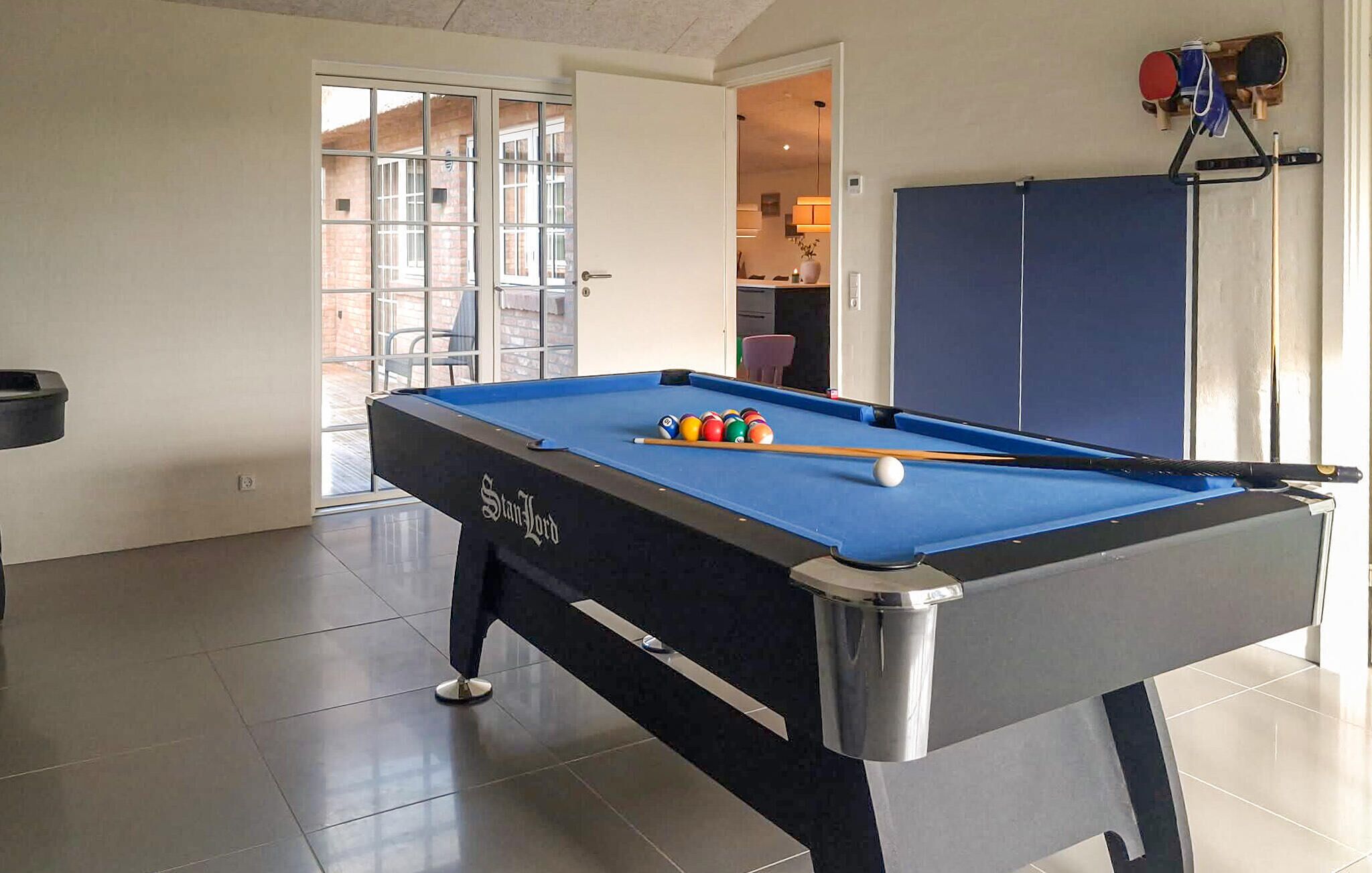 Une table de billard avec des billes, une porte et une vue sur l’extérieur.