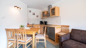 Une cuisine compacte avec des meubles en bois, une table à manger avec des chaises, un canapé et un petit comptoir.