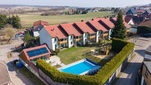 Un immeuble résidentiel doté d’une piscine, de panneaux solaires et d’une cour clôturée.