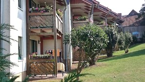 Un immeuble à plusieurs étages doté de balcons, d’une clôture en bois et d’une cour verdoyante.