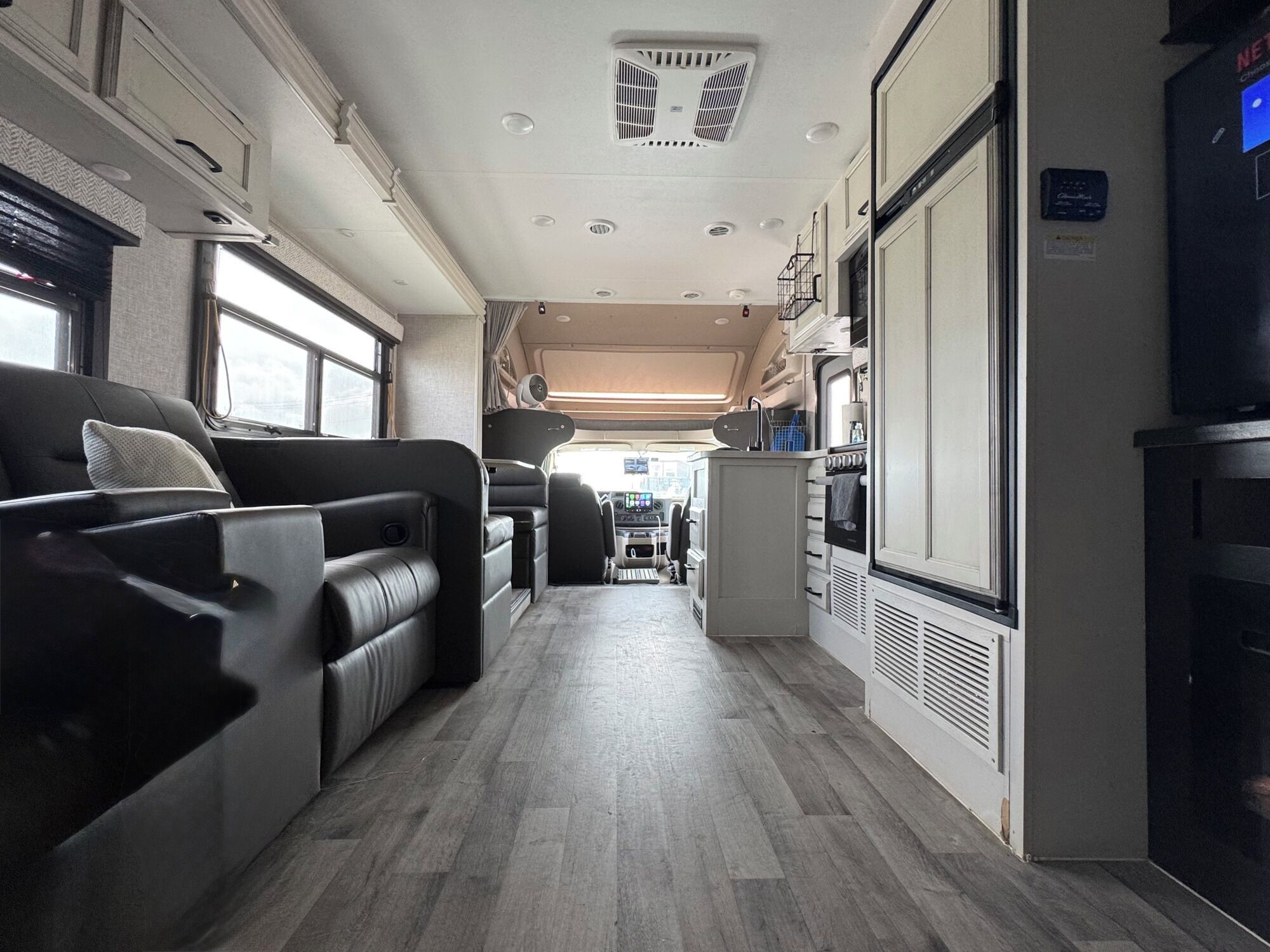 Interior moderno de uma RV com cozinha, área de estar e um pequeno espaço de jantar.