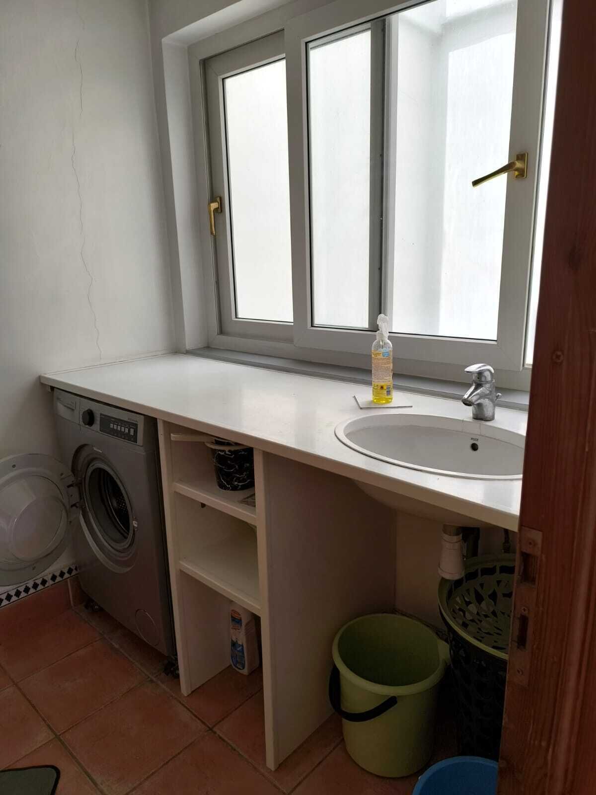 Une petite salle de bain équipée d’un lave-linge, d’un lavabo et d’une fenêtre.