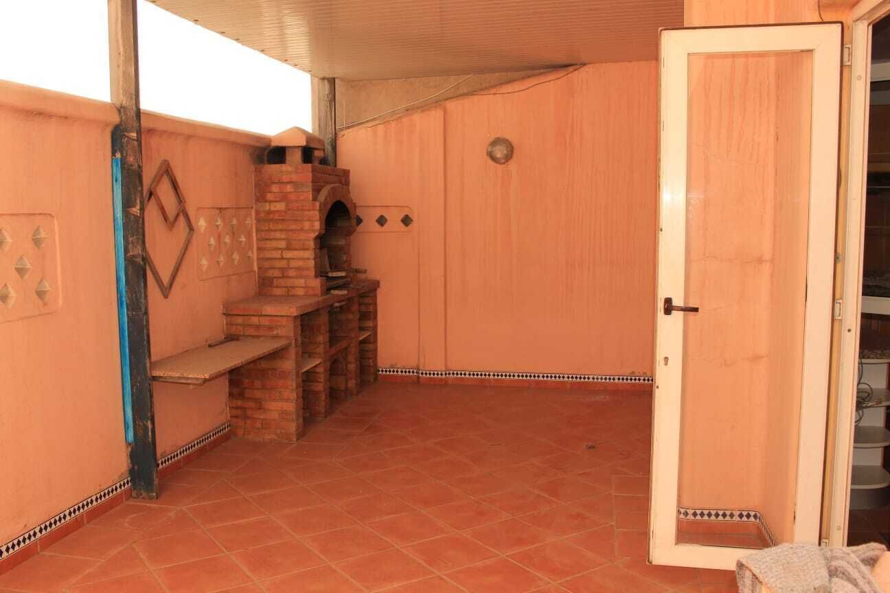 Une pièce avec un sol carrelé, une cheminée en briques, une porte en bois et un banc.