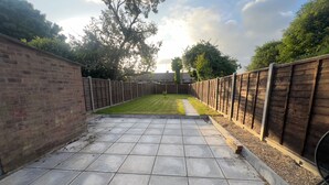 Une terrasse dallée, avec une pelouse et un mur en briques d’un côté.