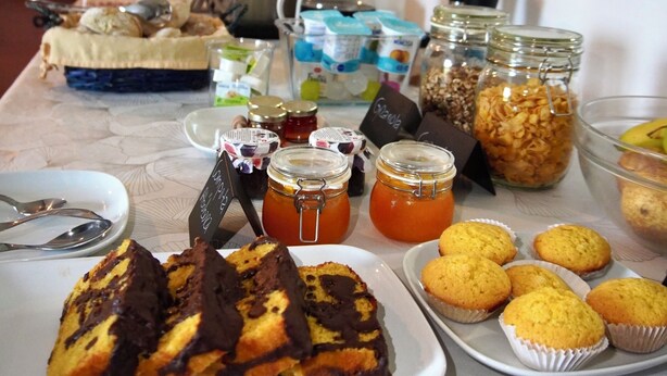 A buffet table with various food items, including pastries, muffins, and jars of spreads. - Herdade da Yucca (Alandroal)