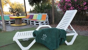 A white lounge chair with a green towel draped over it, set on artificial grass. - Herdade da Yucca (Alandroal)