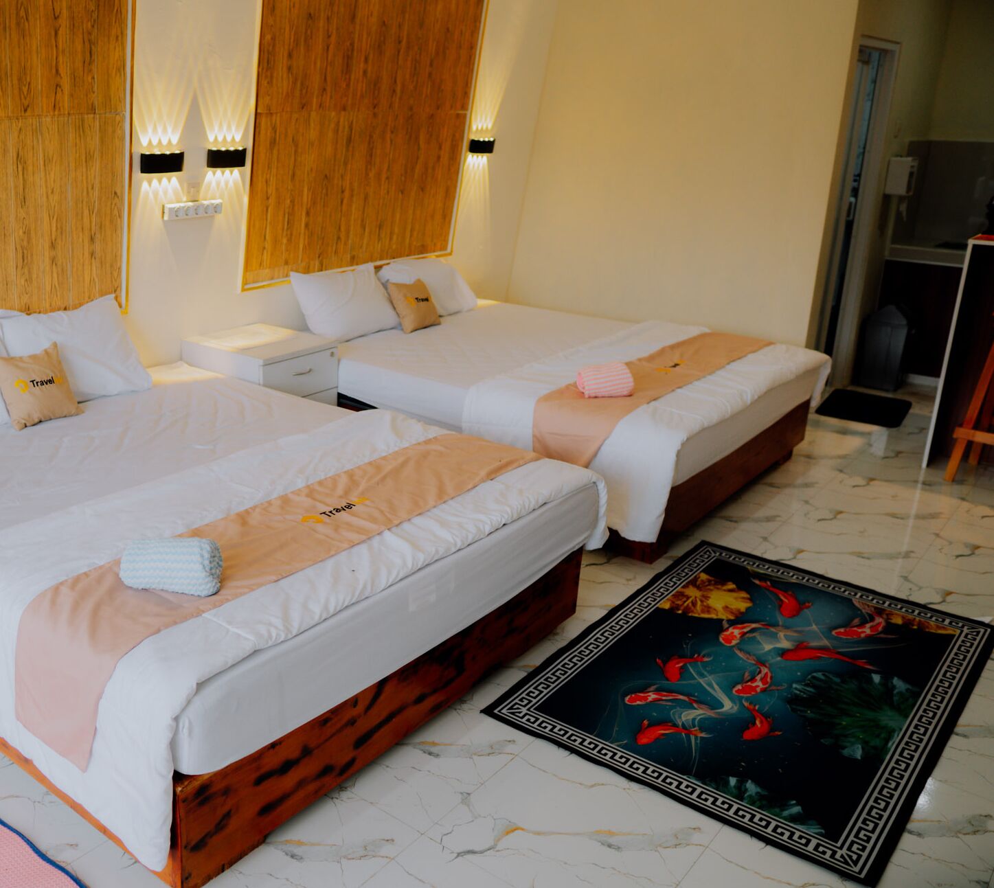 Two single beds with white linens, a wooden headboard, and a decorative rug with a fish design.