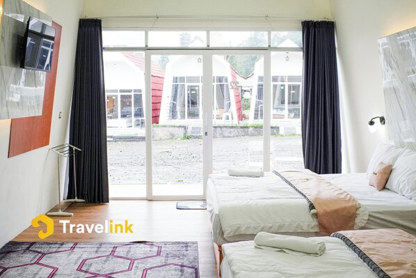 A hotel room with two beds, a TV mounted on the wall, and a large sliding glass door leading to an outdoor area. - Dieng Luxury Camp By Travelink (Kejajar)
