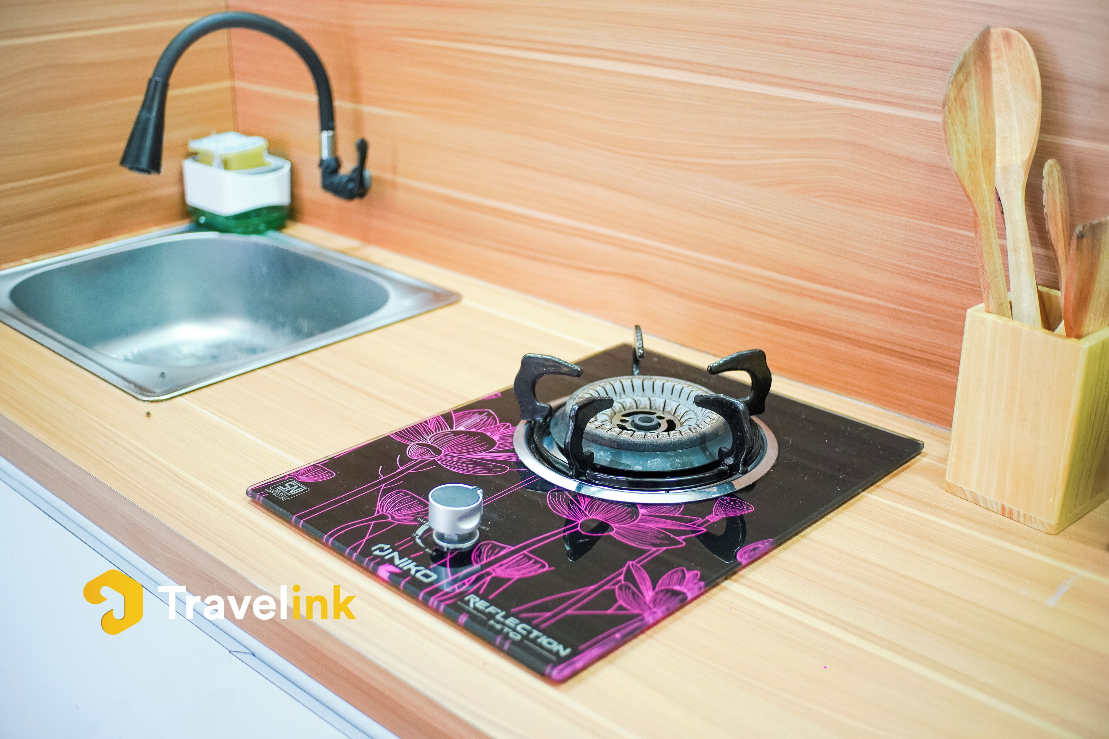 Una cocina con estufa a gas, un lavamanos y utensilios de madera.