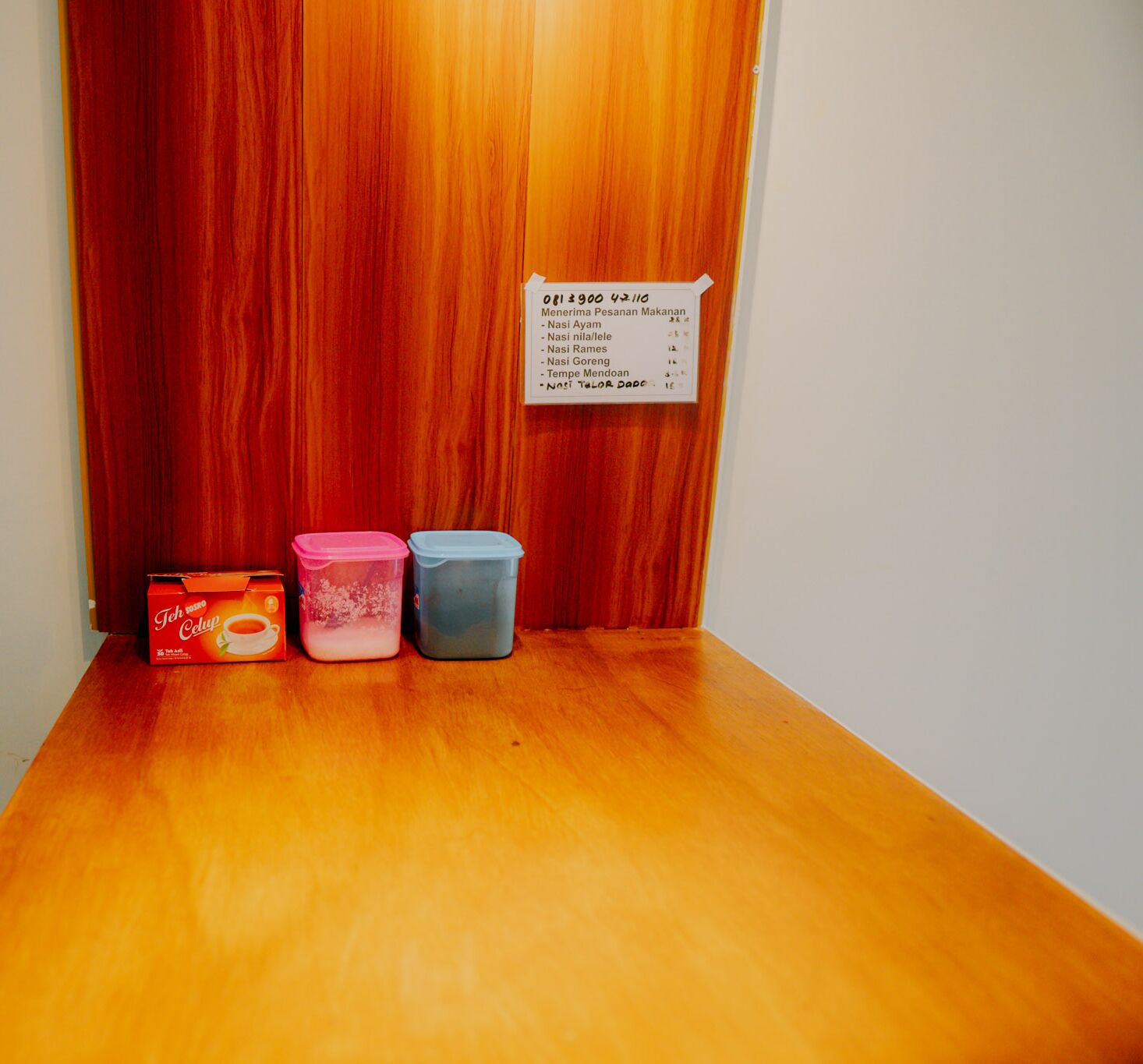 A wooden floor with three containers and a sign listing room numbers.