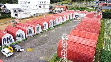 A row of red-roofed cabins with white walls, arranged in a linear fashion along a dirt path.