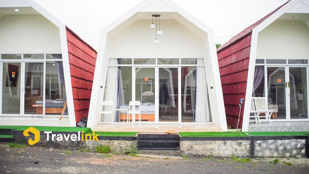 A modern building with a sloped roof, large windows, and a small porch area with chairs. - Dieng Luxury Camp By Travelink (Kejajar)