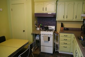 Une cuisine de taille réduite, équipée d’une cuisinière à gaz, d’un évier et d’une table à manger.