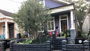 A residential house with a porch, a black metal gate, and a small garden area. - Cozy, Humble 1-Bedroom Near Ferry - Great for Travel Nurses! (New Orleans)
