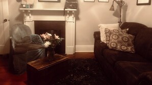 A living room with a fireplace, a sofa, a chair, and a coffee table. - Cozy, Humble 1-Bedroom Near Ferry - Great for Travel Nurses! (New Orleans)