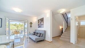 A modern living room with a grey sofa, a dining table with chairs, a staircase, and a balcony with outdoor furniture. - Charming 4-BR Villa with Heated Pool and Sea Views, Close to Beach (Milna)