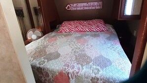 A bedroom with a bed, a wall-mounted sign, and a fan.