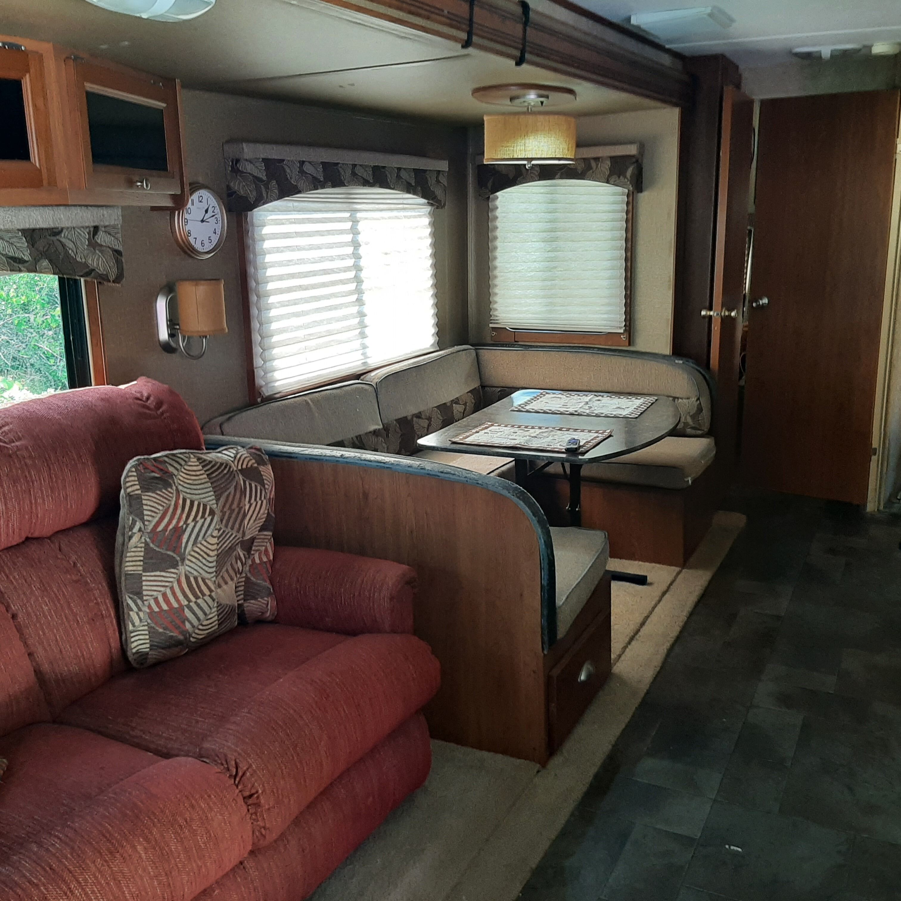 Un intérieur de camping-car compact comprenant un coin cuisine, un espace repas et un coin salon avec un canapé et une table.