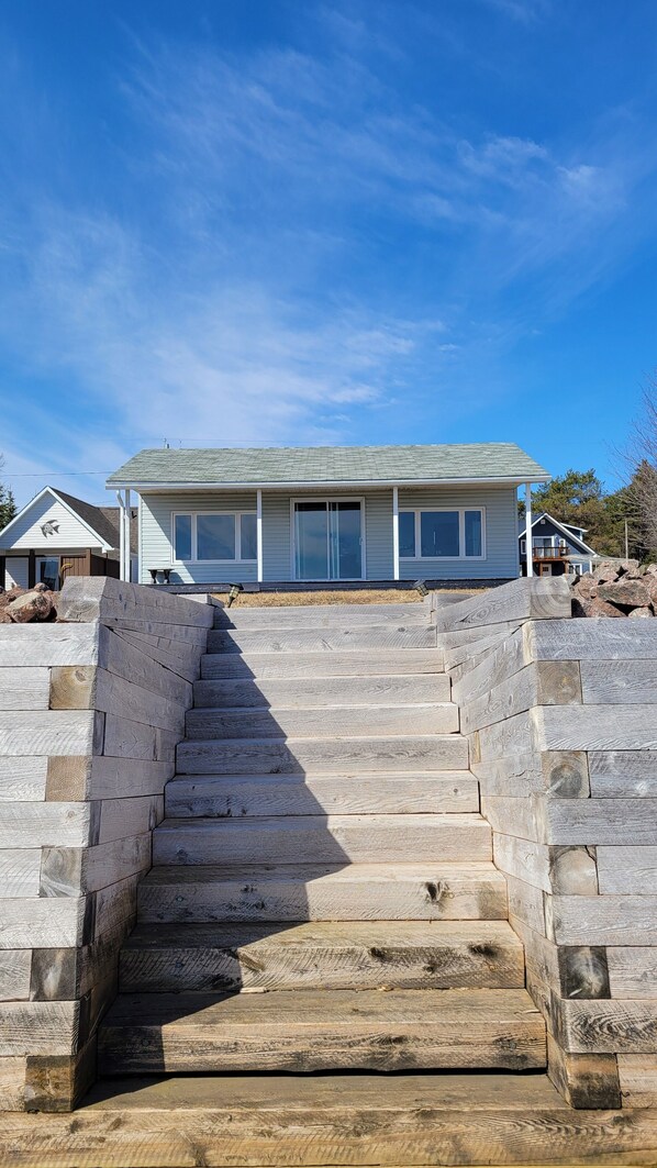 A staircase leading to a house with a gabled roof and large windows.