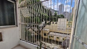 A balcony with a metal railing, a potted plant, and a view of neighboring buildings. - SUH Copacabana 105 Metro Posto 5 (Rio de Janeiro)